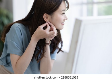 A Woman Getting Dressed In Front Of A Mirror