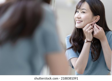 A Woman Getting Dressed In Front Of A Mirror