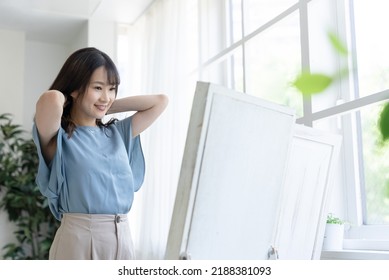 A Woman Getting Dressed In Front Of A Mirror