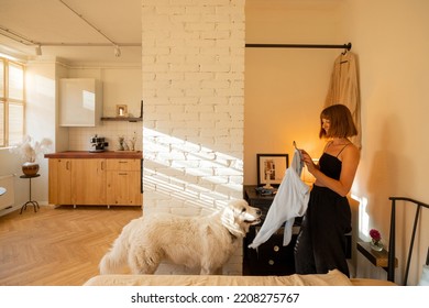 Woman Is Getting Dressed In Wardrobe With Her Dog In Stylish Studio Apartment. Interior Design And Domestic Lifestyle Conept