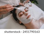 Woman getting facial care by beautician at spa salon. Face peeling mask, spa beauty treatment, skincare.