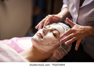 woman getting facial care peeling mask by beautician at spa salon - Powered by Shutterstock