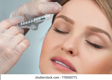 Woman Is Getting Filler Injection Over Eyebrow. Anti-aging Treatment And Face Lift. Cosmetic Treatment. Facial Skin Lifting Injection To Woman's Face. Plastic Surgery