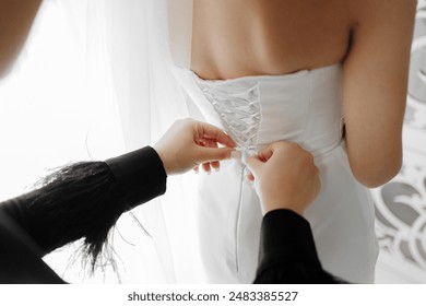 A woman is getting her dress altered by another woman. The woman altering the dress is wearing a black jacket