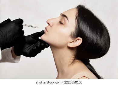 A Woman Getting Her Eyebrows Done By A Professional Make - Up Artist With Black Gloves And A Sy In Her Mouth