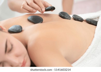 Woman Getting Hot Stone Massage Treatment By Professional Beautician Therapist In Spa Salon. Luxury Wellness, Back Stress Relief And Rejuvenation Concept.