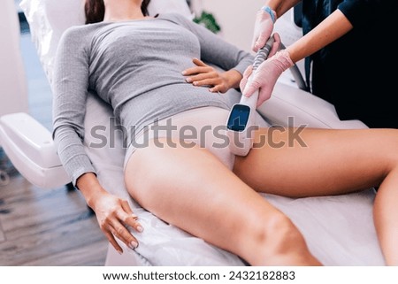 Woman getting a laser bikini area hair removal procedure by a professional beautician in a beauty salon.