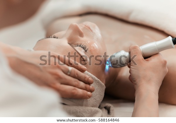 Woman getting laser and\
ultrasound face treatment in medical spa center, skin rejuvenation\
concept