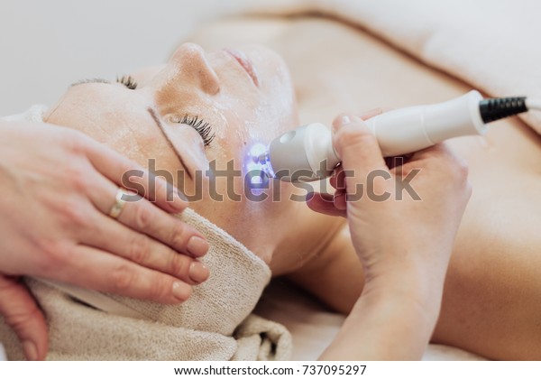 Woman getting laser and ultrasound face treatment\
in medical spa center