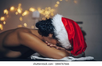 Woman getting massage in Christmas spa. Spa concept. Massage. Santa hat. Christmas time. 
