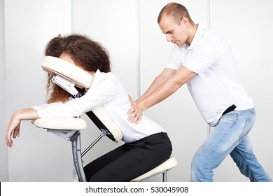 Woman getting mobile chair massage by man in office