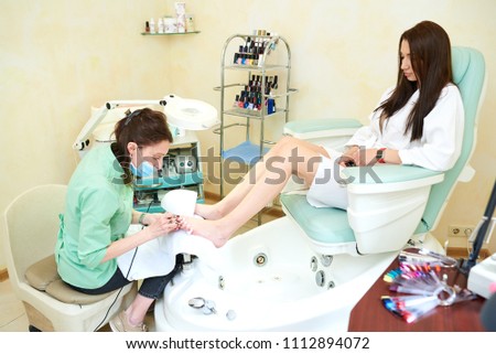 Woman getting a pedicure and relaxing at the beauty salon. Professional pedicure master. Patient on medical pedicure procedure, visiting podiatrist. Foot treatment in SPA salon. Podiatry clinic.