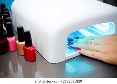 Woman getting professional manicure in beauty salon, master applies gel polish on nails and dry in a uv lamp, nail extension tools - Powered by Shutterstock