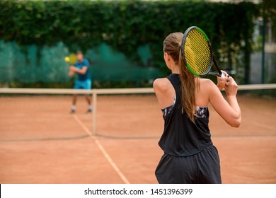 Woman Getting Ready To Retrieve A Ball During A Match, Forehand Shot. Back View On A Female Tennis Player At Outdoor Court.