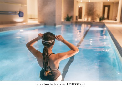 Woman getting ready to swim in indoor swimming pool at hotel or apartment building complex - condo amenities.