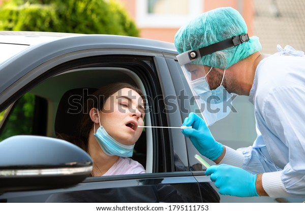 Woman getting tested at a coronavirus\
drive thru station by medical staff with PPE suit by throat swab.\
Health care drive thru service and medical\
concept