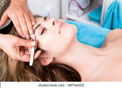 Woman Getting Tweezing Eyebrow By Beautician