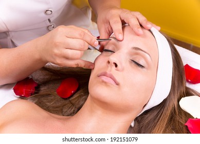 Woman Getting Tweezing Eyebrow By Beautician.