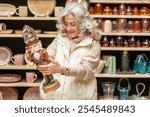 A woman in a gift store, holding and examining a Nutcracker figurine with a snowy glass ball with dancing figures on its head