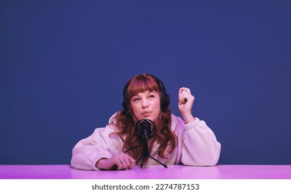 Woman with ginger hair whispering into a microphone as she records an asmr podcast. Female content creator hosting a relaxing audio broadcast for her social media fanbase. - Powered by Shutterstock