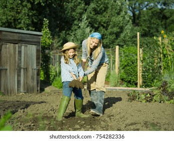 A Woman And Girl Digging A Garden