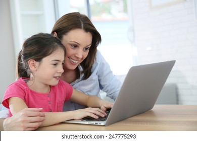 Woman with girl doing homework on laptop