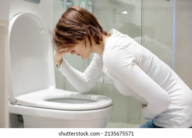 Woman, girl, experiencing sickness, vomiting, pregnancy, poisoning and morning discomfort, sitting over the toilet