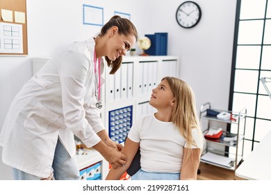 Woman And Girl Pediatrician And Patient Putting Band Aid On Arm At Clinic