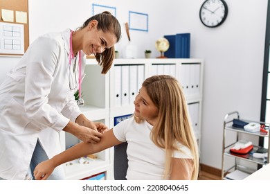 Woman And Girl Pediatrician And Patient Putting Band Aid On Arm At Clinic