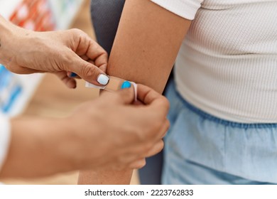 Woman And Girl Pediatrician And Patient Putting Band Aid On Arm At Clinic