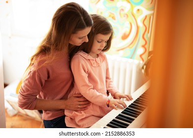 Woman and girl playing a piano. Beautiful mom teaching her daughter playing a piano. - Powered by Shutterstock