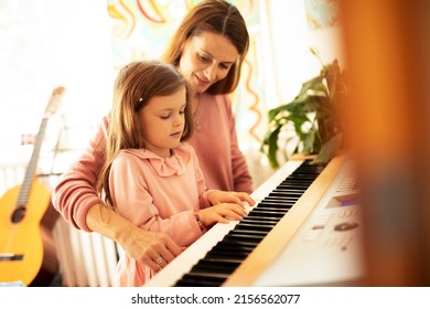 Woman and girl playing a piano. Beautiful woman teaching a little girl playing a piano. - Powered by Shutterstock