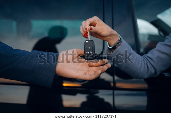Woman give car keys to man. Hands hold car keys.\
Car rental