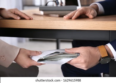 Woman Giving Bribe To Man Under Table In Office, Closeup