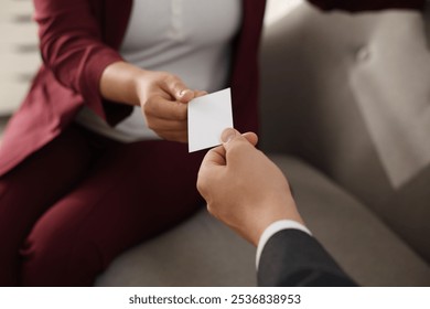 Woman giving business card to man in office, closeup. Mockup for design