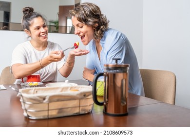 Woman giving food to her lesbian couple during breakfast in a table at home - Powered by Shutterstock