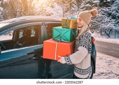 Woman Giving Gifts. Female Is Holding Presents And Delivering Them On Her Car To Home. Holidays Concept. Driving Car In Christmas Eve. People In A Snow-Covered Forest. Sunny Cold Winter Day.