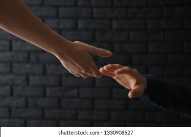 Woman giving hand to depressed man against dark background. Suicide prevention concept