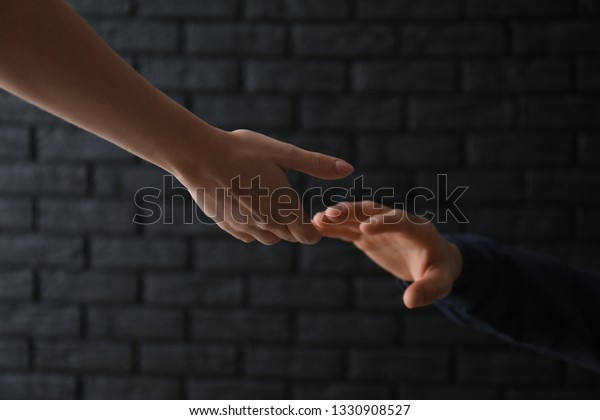 Woman giving hand to depressed man
against dark background. Suicide prevention
concept