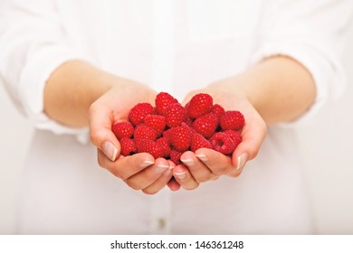 Woman giving a handful of raspberries