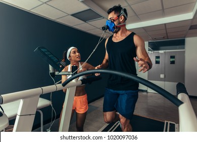 Woman giving instruction to male runner on treadmill in laboratory. Runner with mask on treadmill in laboratory with woman trainer. - Powered by Shutterstock