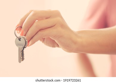 Woman giving key. Female hand holding key from new apartment. Cropped shot, closeup. Property buying or mortgage concept