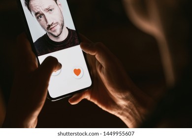 Woman giving a like to photo on social media or swiping on online dating app. Finger pushing heart icon on screen in smartphone application. Friend, follower or fan liking picture of a beautiful man. 