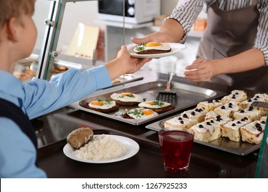 Woman giving plate with healthy food to boy in school canteen, closeup - Shutterstock ID 1267925233