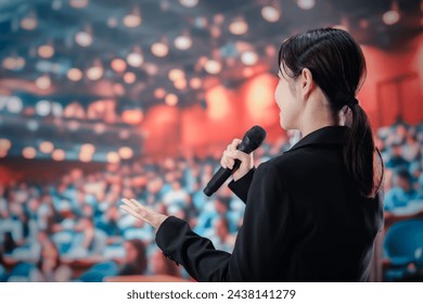 Woman giving a speech in front of a large audience - Powered by Shutterstock