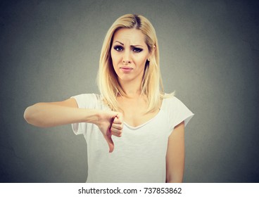 Woman giving thumb down gesture looking with negative expression and disapproval isolated on gray background - Shutterstock ID 737853862
