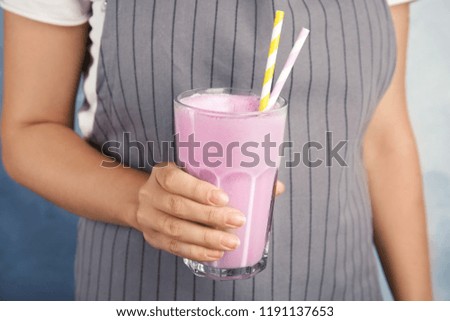 Woman with glass of delicious milk shake on color background, closeup