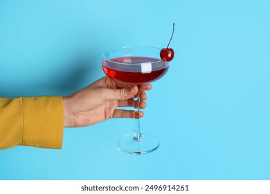 Woman with glass of refreshing cocktail on light blue background, closeup - Powered by Shutterstock