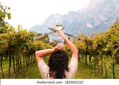 Woman with a glass of white wine in the vineyards of Italy. Soft focus on the person.