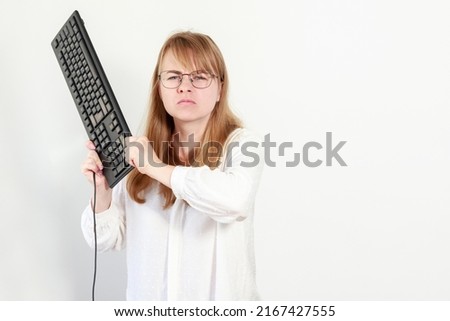 woman in glasses with a keyboard from a computer is not satisfied and aggressive
